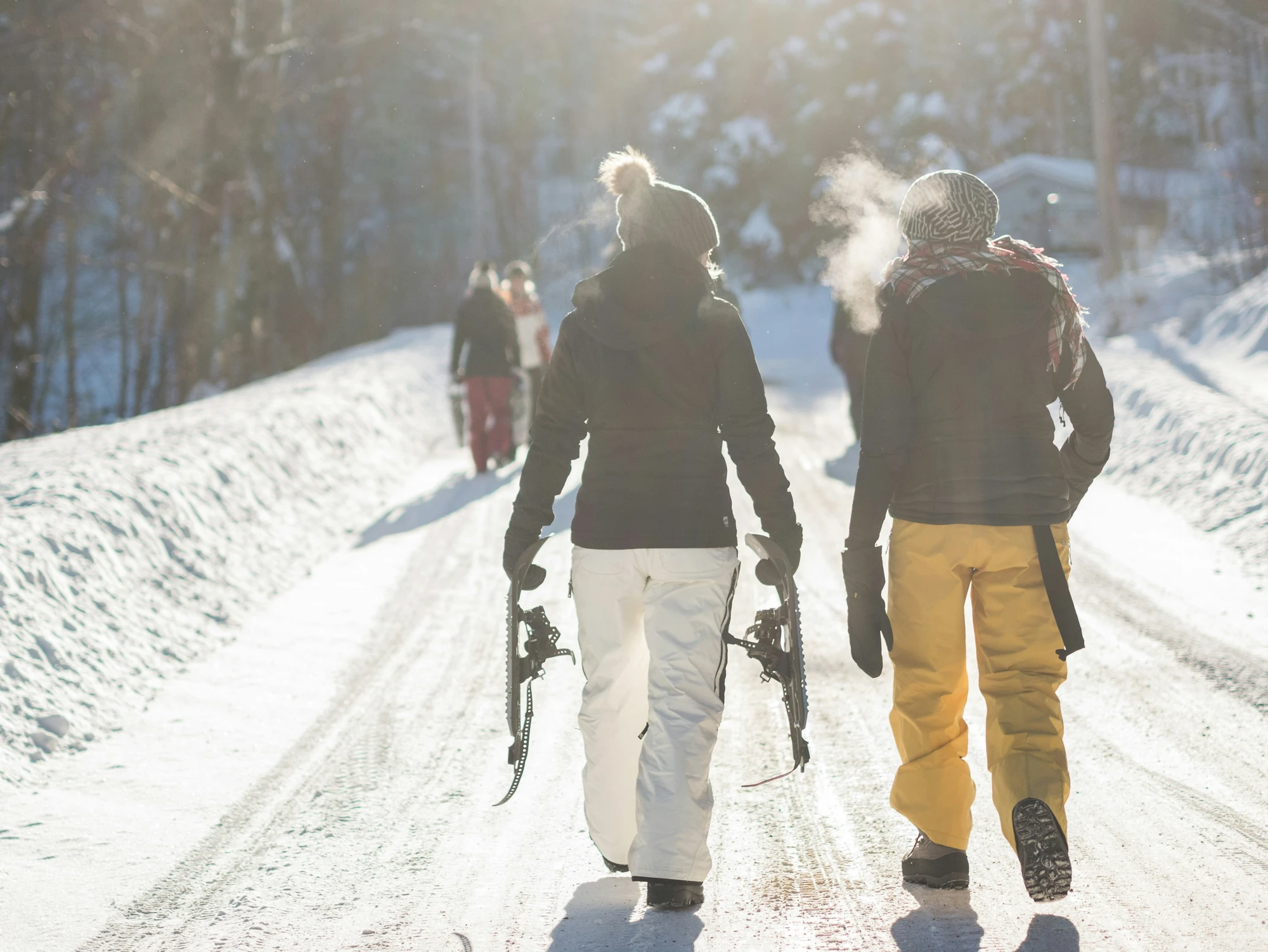 2 junge Frauen unterhalten sich bei eiskalten Temperaturen und Sonnenschein bei einer Schneewanderungen und tragen Schneeschuhe.