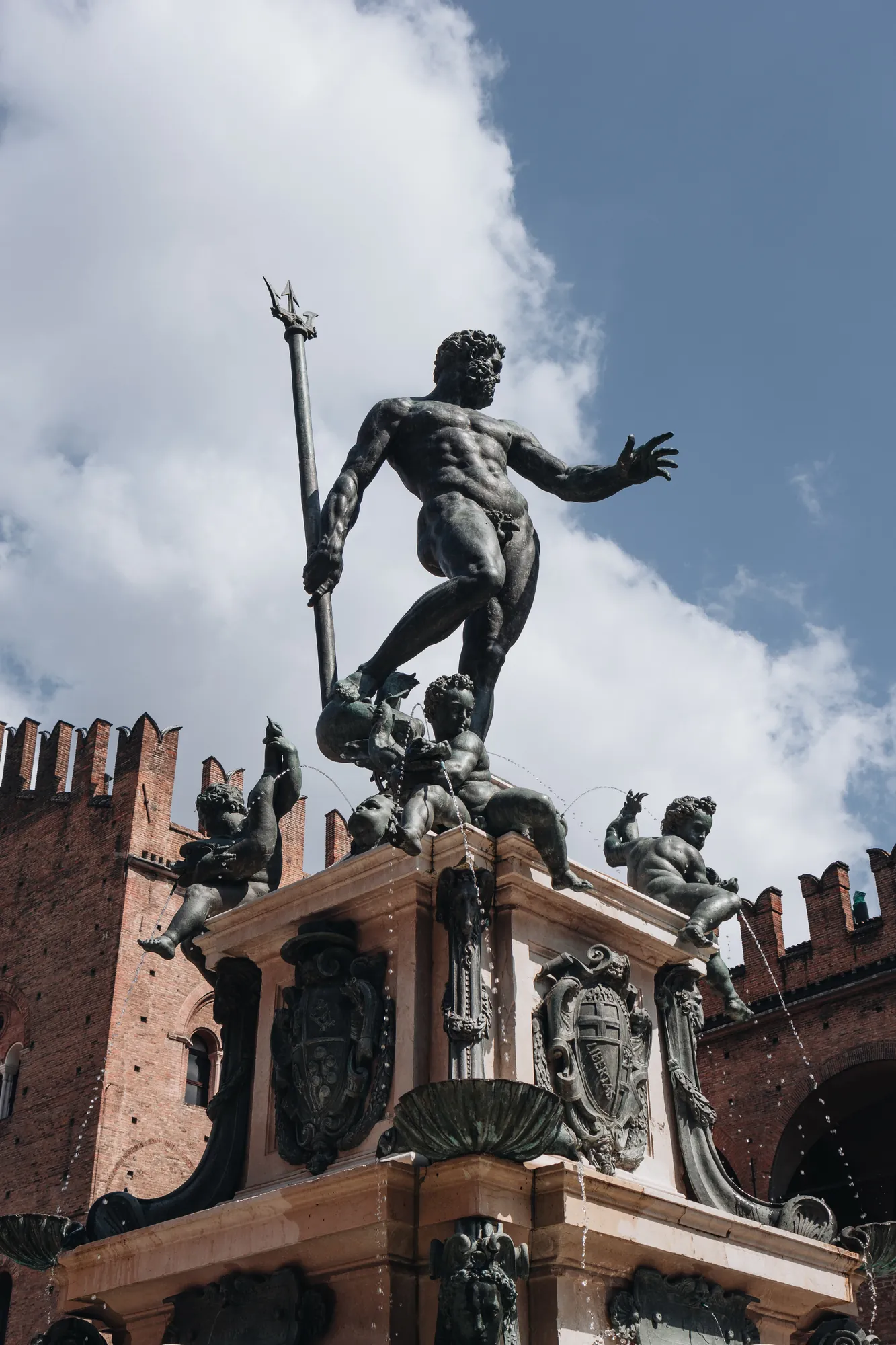 Nahaufnahme der Neptun-Skulptur am Neptunbrunnen in Bologna. Die detailreiche Darstellung des mächtigen Meeresgottes, umgeben von kunstvollen Verzierungen, fängt die beeindruckende Handwerkskunst und die Dynamik der Skulptur eindrucksvoll ein.