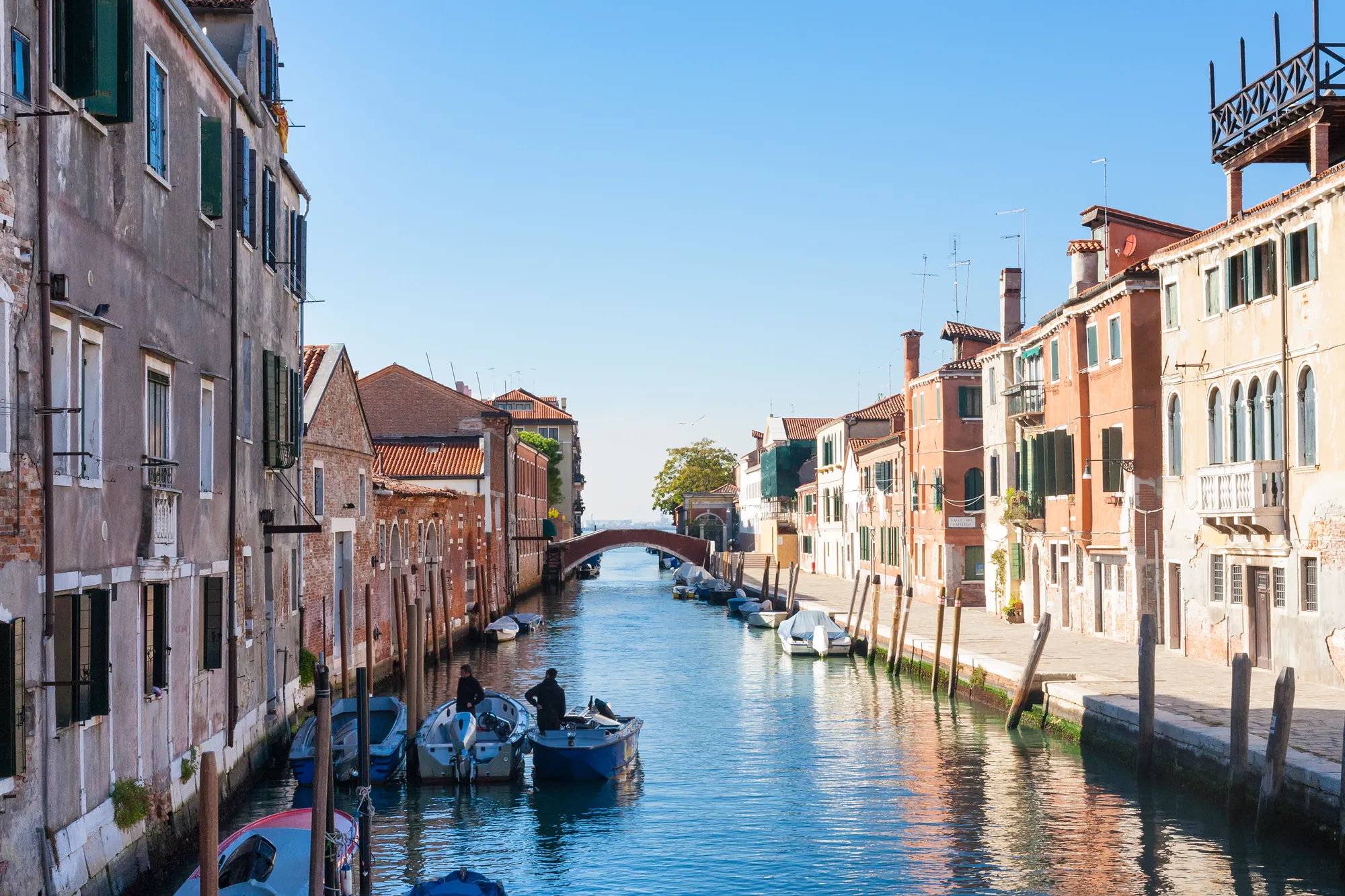 An einem sonnigen und klaren Tag zeigt das Cannaregio Stadtviertel in Venedig den Canal Grande mit angelegten Booten. Links und rechts säumen farbenfrohe Häuserreihen den Kanal, die das venezianische Flair unterstreichen.