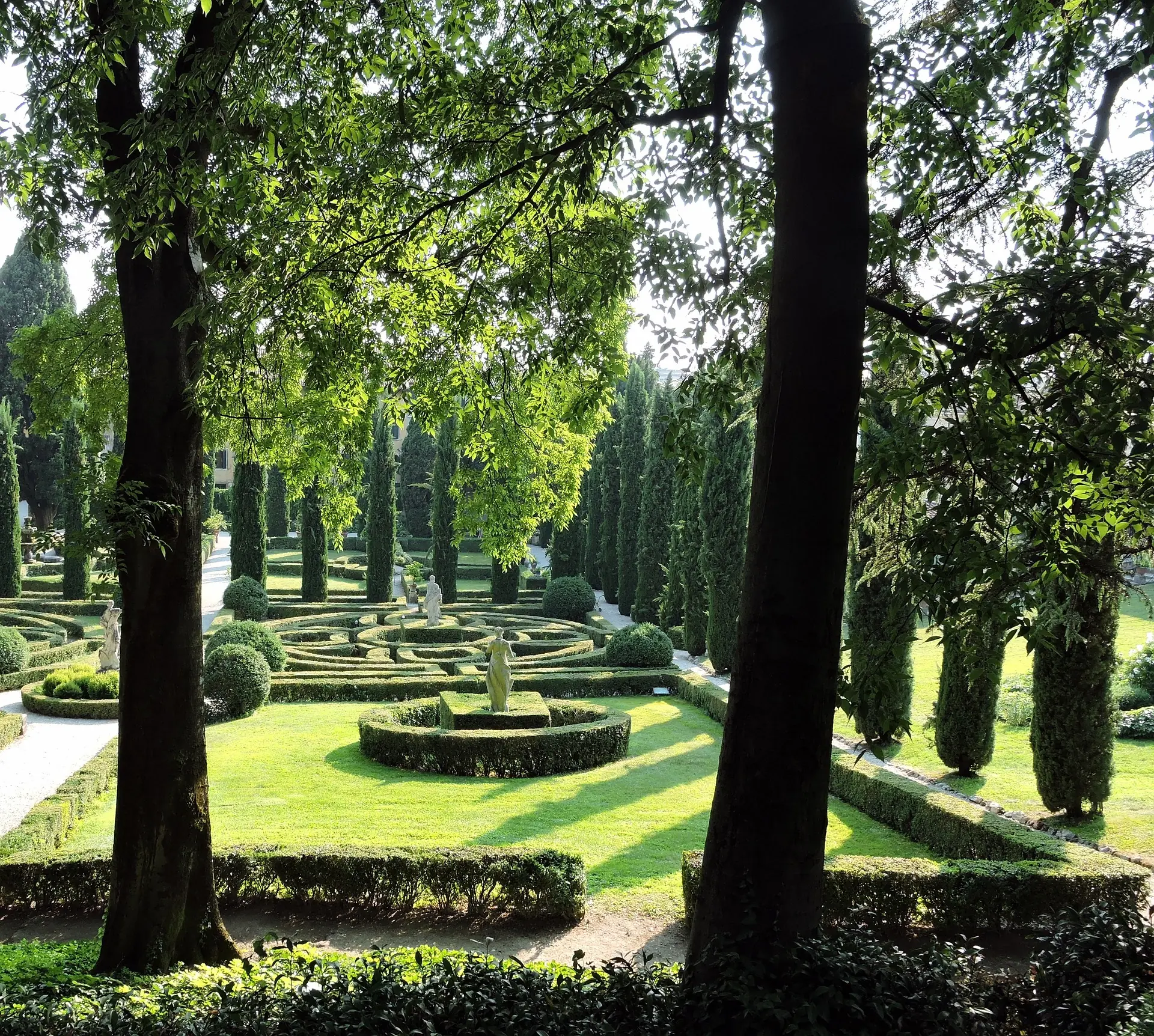 Der Giardino Giusti, ein malerischer Renaissance-Garten in Verona, erstrahlt im hellen Tageslicht. Die sorgfältig gestalteten Pflanzenarrangements und historischen Elemente schaffen eine harmonische Atmosphäre, umgeben von üppigem Grün.