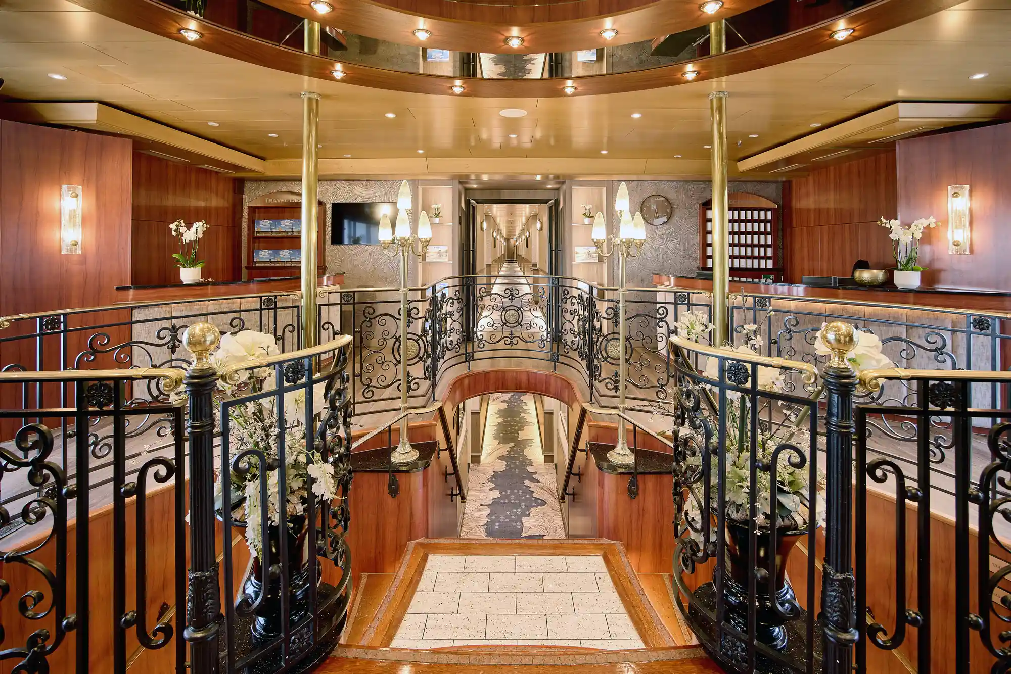 Stilvolle Lobby auf einem Kreuzfahrtschiff mit eleganten Lampen und Blumen.