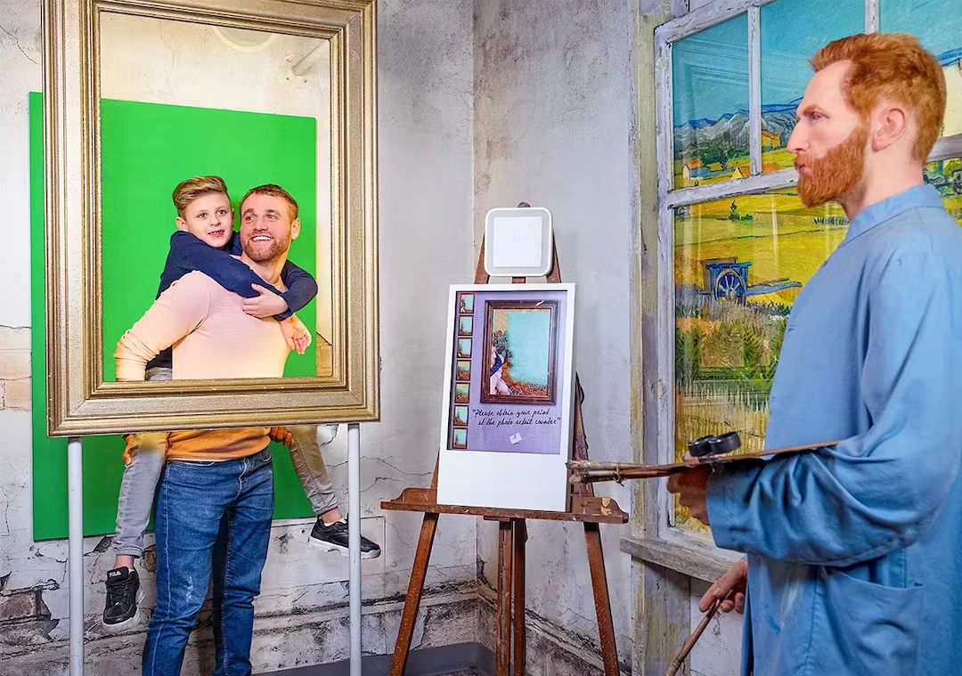 Wachsfigurenkabinett Madame Tussauds Amsterdam - Vincent Van Gogh in seinem Atelier. Im Hintergrund Vater und Sohn in einem Bilderrahmen, sodass es aussieht als zeichne Van Gogh diese.