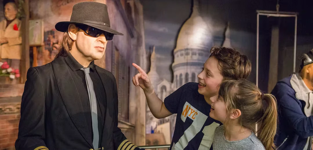 Wachsfigurenkabinett Panoptikum Hamburg - Ein Junge und ein Mädchen betrachten die Figur Udo Lindenbergs, der klassisch Anzug, Schlapphut und Sonnenbrille trägt.