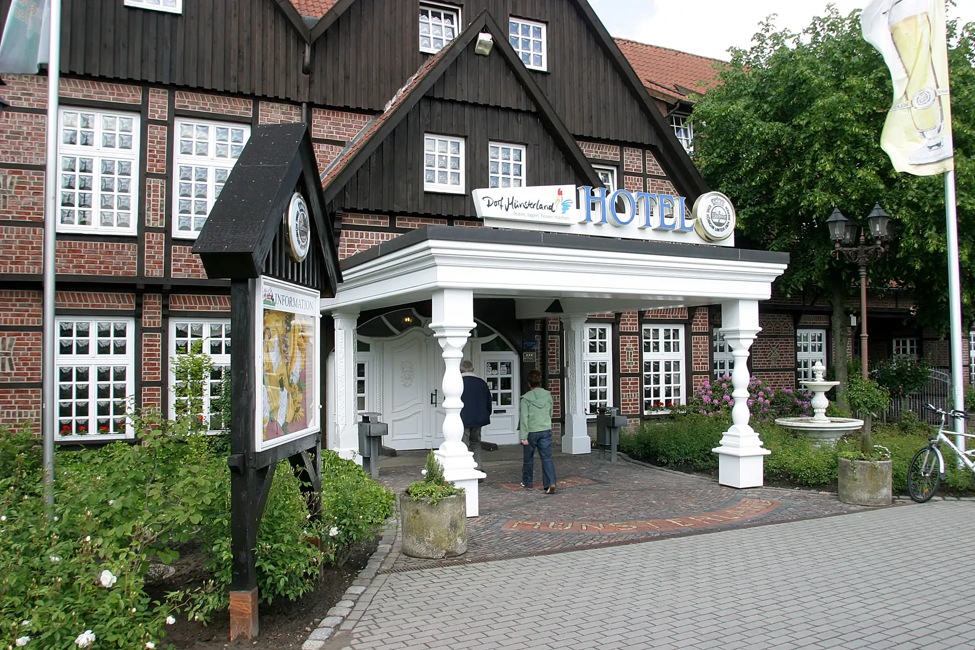 Eingangsbereich des Welcome Hotel Legden mit Fachwerkhaus, weißem Vordach und Schild mit der Aufschrift 'HOTEL'