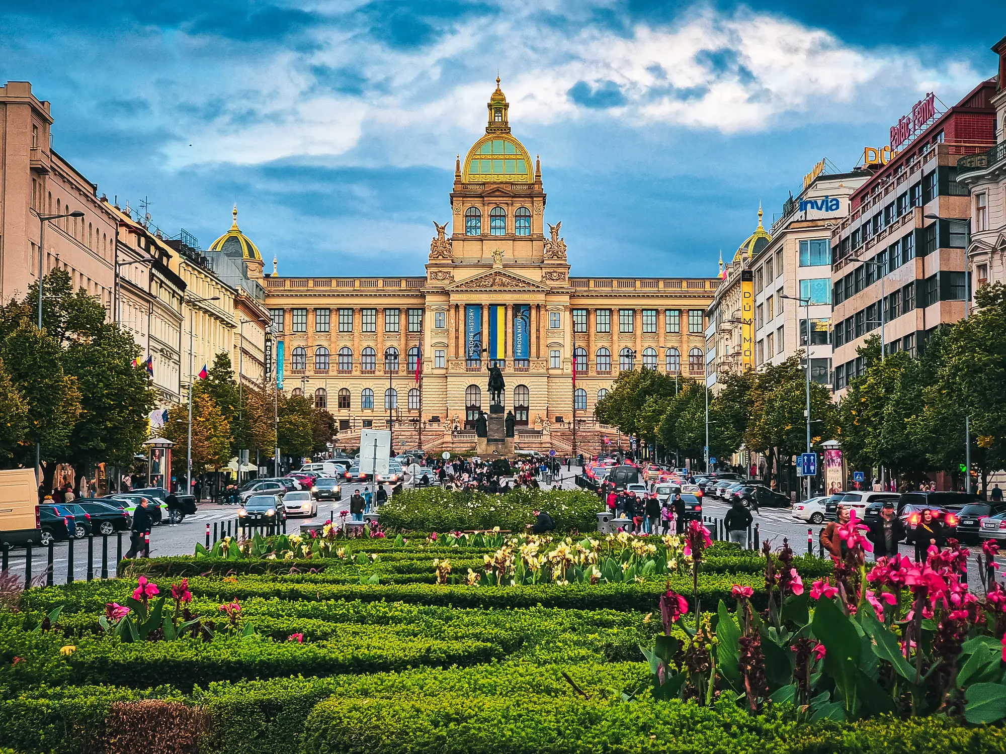 Prag - Wenzelplatz, historisches Gebäude im Hintergrund, Garten im Vordergrund und Menschen an den Seiten