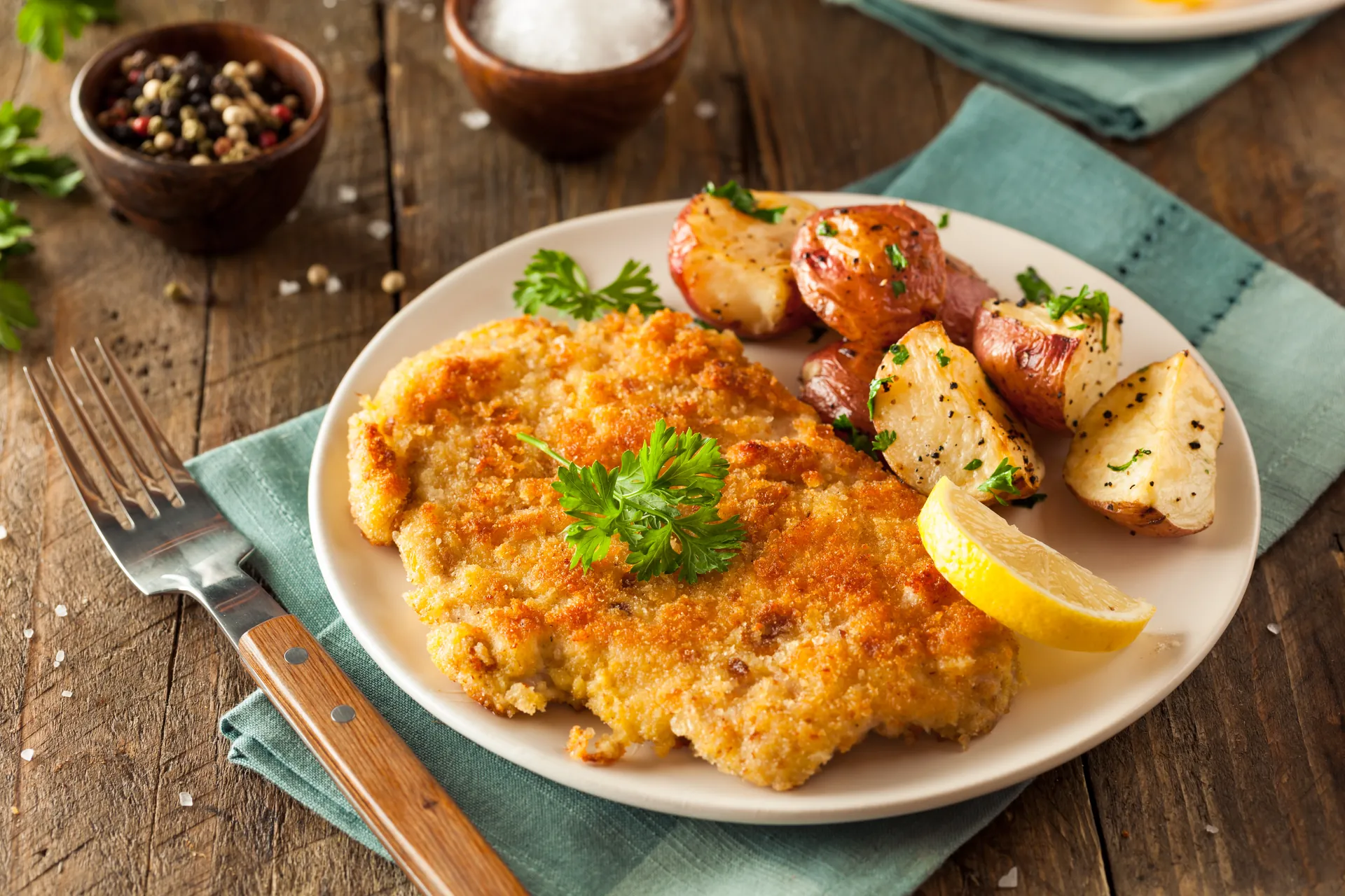 Wiener Schnitzel mit Röstkartoffeln angerichtet auf einem Holztisch