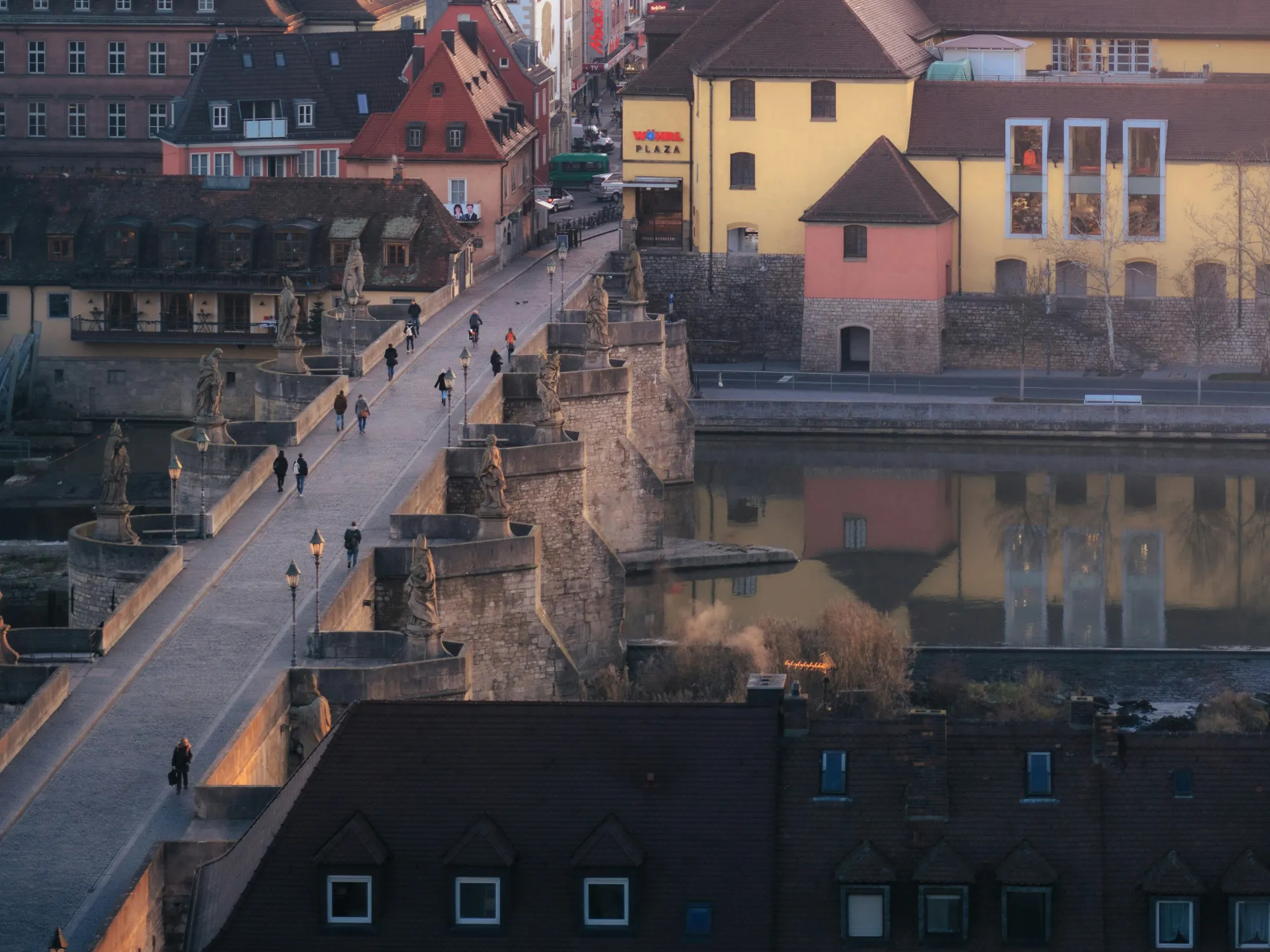 Malerischer Blick auf die Würzburger Altstadt im sanften Licht des Sonnenuntergangs, mit der Alten Mainbrücke im Vordergrund und den markanten Türmen der Stadt im Hintergrund.
