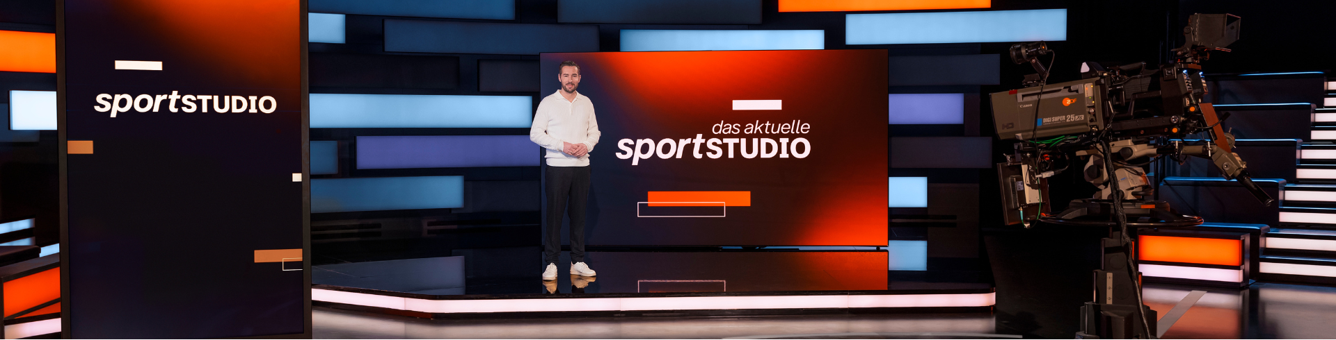 Moderner Fernsehstudio mit einem Moderator vor einem großen Bildschirm, der 