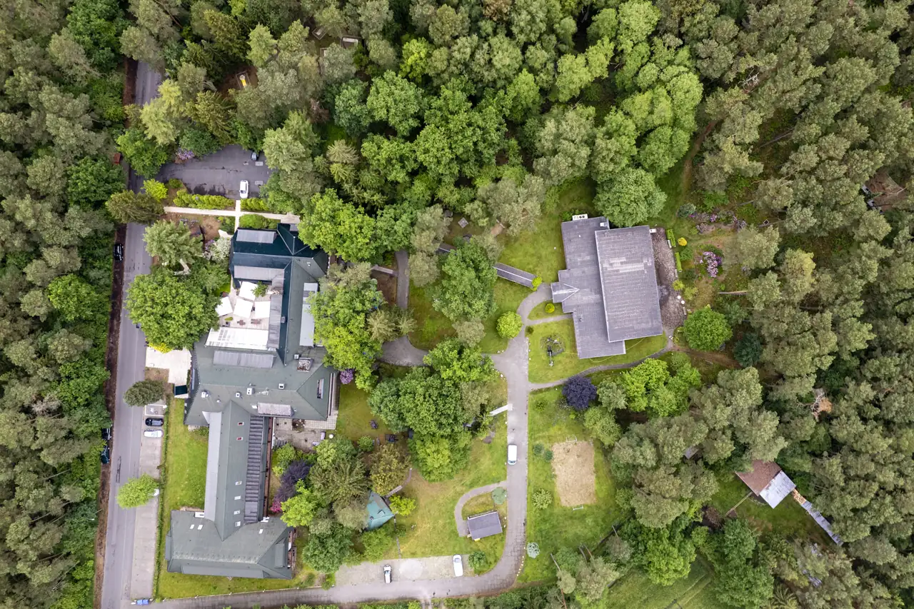 Luftaufnahme des Hotels Zur Heidschnucke umgeben von dichtem Wald mit mehreren Gebäuden, Wegen und Parkplätzen