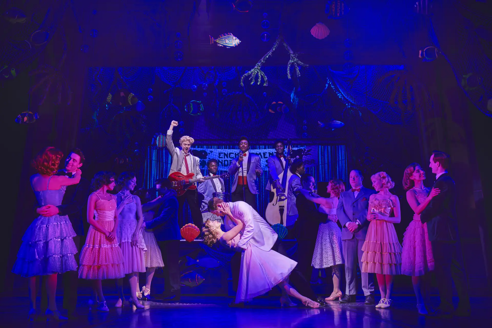 Zurück in die Zukunft – Das Musical, Szenenmotiv: Cast (Sarah Goggin als Lorraine Baines, Orlando Gibbs als George McFly & weitere) in 1950er-Jahre-Kleidung, ein Paar tanzt im Vordergrund, andere stehen im Halbkreis und beobachten